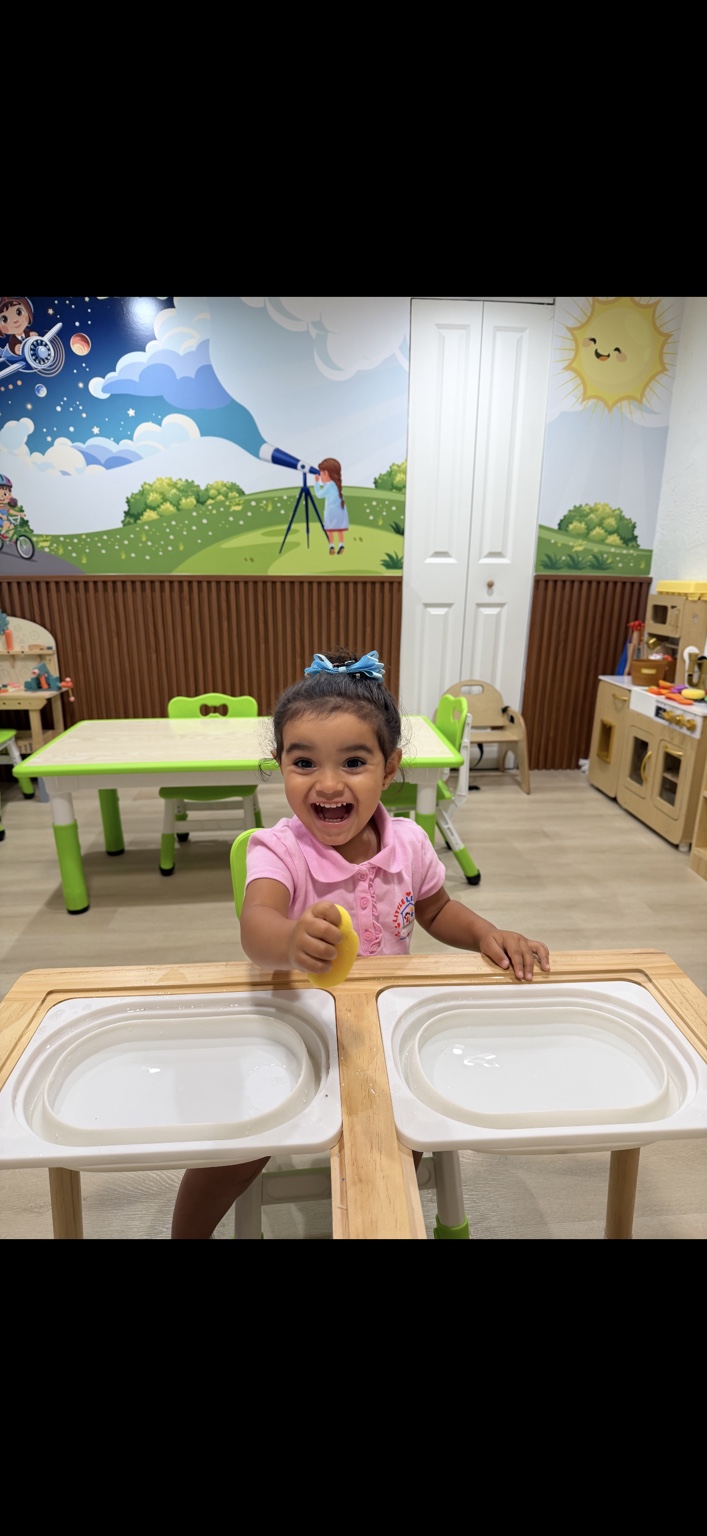 A smiling Little Learners child exploring a sensory play table